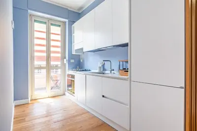 a kitchen with white cabinets and blue walls at Luciano Boutique Apartment in Rome