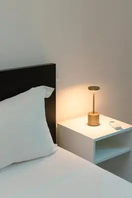 a bed with a white pillow and a night stand at Tiber Luxury Apartment in Rome