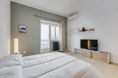 a white bedroom with a large bed and a television at Domus Suite Gemelli - Relax & Comfort in Rome