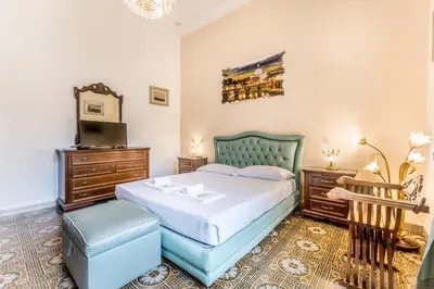 a bedroom with a bed and a chair and a television at Dimora Armanda Roma in Rome