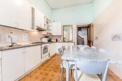 a kitchen with white cabinets and a table and chairs at Dimora Armanda Roma in Rome