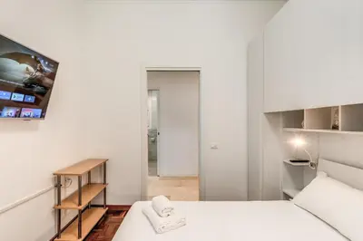 a small white bedroom with a bed and a table at Maison Sofia in Rome