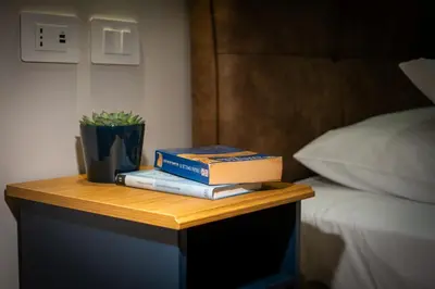two books sitting on a table next to a bed at The Suitest Roma Apartment Appio Latino in Rome