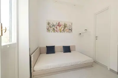 a white room with a couch with blue pillows on it at Nexus Prati Suite in Rome