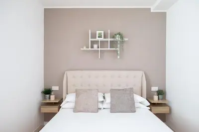 a white bedroom with a white bed with two pillows at iFlat Modern Sunlit Studio Apt by the Colosseum in Rome