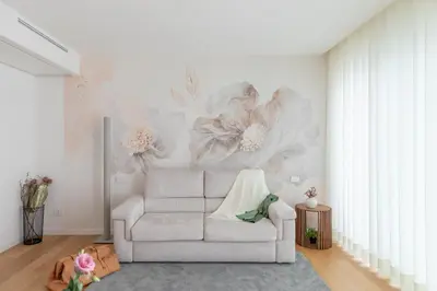 a living room with a white couch and flowers on the wall at iFlat Modern Sunlit Studio Apt by the Colosseum in Rome