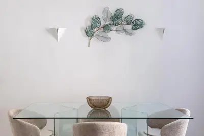 a glass table with chairs and a plant on a wall at iFlat Sleek & Sunlit Apartment near the Vatican in Rome