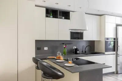 a kitchen with white cabinets and a black counter top at iFlat Sleek & Sunlit Apartment near the Vatican in Rome