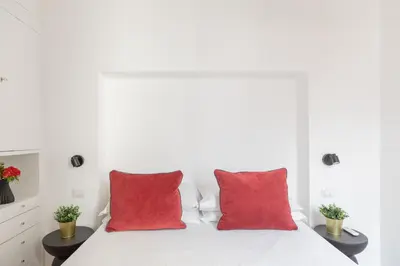 a white bedroom with red pillows on a bed at iFlat Peaceful & Charming Hideaway near Vatican in Rome