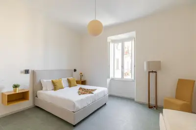 a white bedroom with a bed and a chair at iFlat Calm & Spacious Apartment in Urban Oasis in Rome
