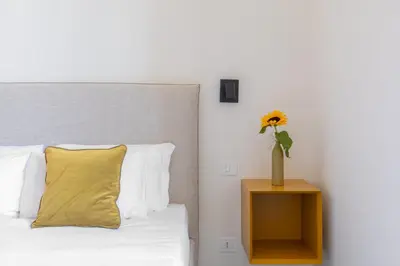 a bed with a yellow pillow and a vase with a flower at iFlat Calm & Spacious Apartment in Urban Oasis in Rome