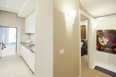a kitchen and a living room with white walls at Modern Flat Historic 1200s Palace Steps from Navona in Rome