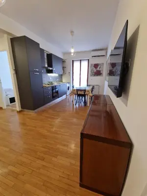 a living room with a table and a kitchen at Ponte Lungo Guest House in Rome