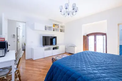 a white bedroom with a blue bed and a tv at Elegante dimora - nel centro di Roma in Rome