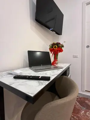 a desk with a laptop and a vase of flowers at Dormire in Trastevere in Rome