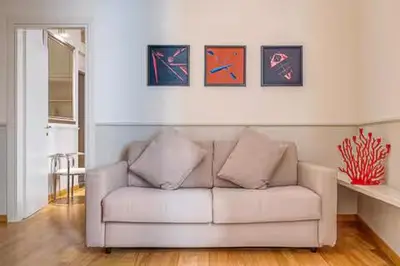 a white couch in a living room with paintings on the wall at Navona Boutique House in Rome