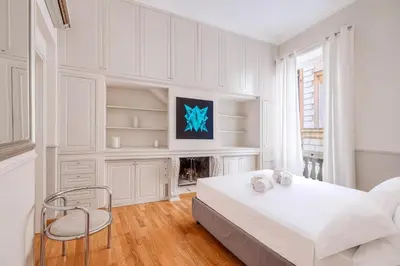 a white bedroom with a large bed and a chair at Navona Boutique House in Rome