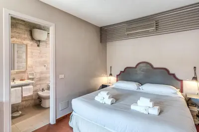 a bedroom with a large bed and a bathroom at Frangipane Colosseum Apartments in Rome