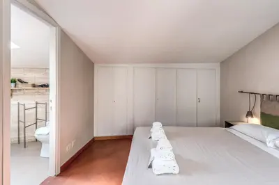 a white bedroom with a bed and a toilet at Frangipane Colosseum Apartments in Rome
