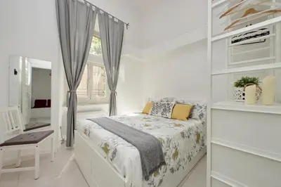 a white bedroom with a bed and a window at Castro Pretorio Sweet Home in Rome