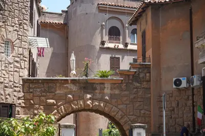 a stone building with an arch in a street at Graziosa camera in posizione strategia con bagno privato esterno in Rome