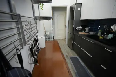 a kitchen with black cabinets and a wooden floor at Graziosa camera in posizione strategia con bagno privato esterno in Rome