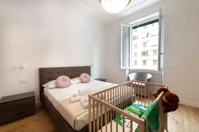 a bedroom with a crib with pink pillows and a window at A Casa Tua Vatican Suite in Rome