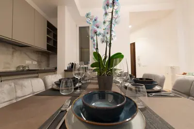 a table with plates and glasses and a vase with flowers at A Casa Tua Vatican Suite in Rome