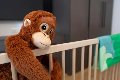 a stuffed monkey is sitting in a crib at A Casa Tua Vatican Suite in Rome