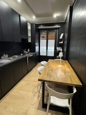 a kitchen with a wooden table and white chairs at Marconi Suite & Charme in Rome