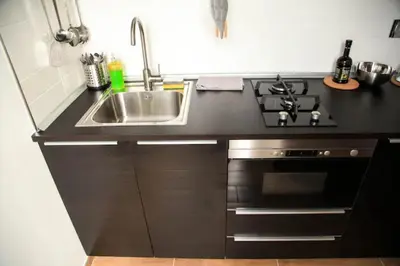 a black kitchen with a sink and a stove at Sunset Home in Rome