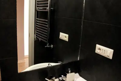 a black bathroom with a sink and a mirror at Sunset Home in Rome