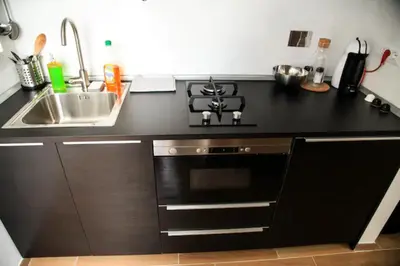 a black kitchen with a sink and a stove at Sunset Home in Rome