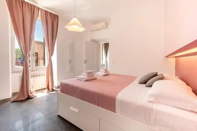 a white bedroom with a bed and a window at Angelina Domus Saint Peter's in Rome