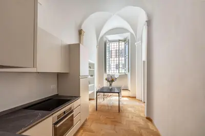 a kitchen with white cabinets and a table with a chair at Casa Paolina, Burghesius homes in Rome