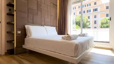 a bed in a room with a large window at Soggiorno Chic , 2 Camere Vicino Colosseo e Metro in Rome