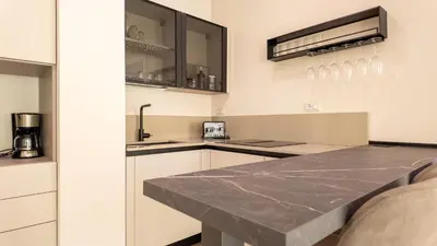 a kitchen with white cabinets and a marble counter top at Soggiorno Chic , 2 Camere Vicino Colosseo e Metro in Rome