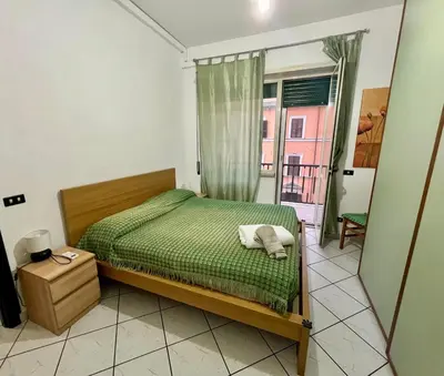 a bedroom with a bed with a green comforter and a window at San Giovanni Apartment in Rome