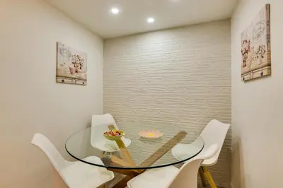 a dining room with a glass table and white chairs at Pica's House in Rome