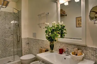 a bathroom with a sink and a vase with white flowers at Casa Sotgiu Guest House in Rome