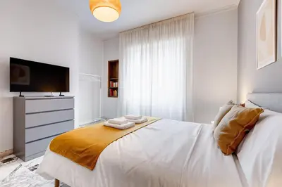 a white bedroom with a bed and a television at FaMa - Quiet&Bright 2BR Apartment in Rome