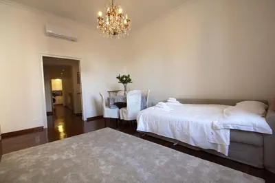 a bedroom with a bed and a table and a chandelier at La Finestra sulla Basilica in Rome