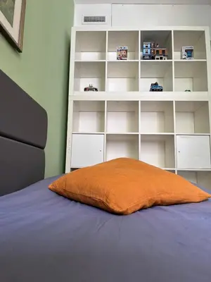 an orange pillow sitting on a bed with a book shelf at Olimpic Sunny room in Rome