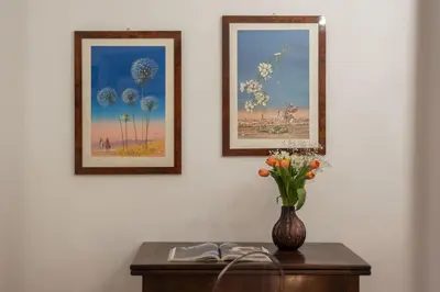 a vase of flowers on a table with two pictures at Casa Fiori - WelcomeToRhome in Rome