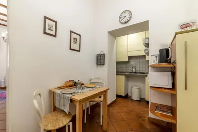 a kitchen with a table and a small kitchen with a clock at Casa Fiori - WelcomeToRhome in Rome