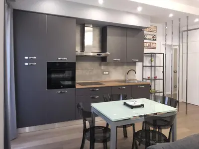 a kitchen with black cabinets and a table with chairs at Patrica house in Rome
