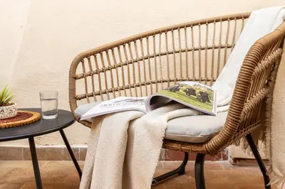 a wicker chair with a blanket and a book on it at NOH Forum Patio in Rome