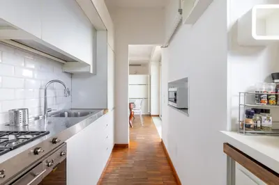 a kitchen with white walls and a wooden floor at Nostromondo BIANCAMANO ATTIC - Stylish penthouse with private terrace- San Giovanni in Rome