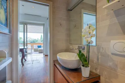 a bathroom with a sink and a vase with flowers on a counter at Nostromondo BIANCAMANO ATTIC - Stylish penthouse with private terrace- San Giovanni in Rome