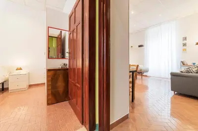 a living room with a wooden door and a bedroom at Casa di Vigo - WelcomeToRhome in Rome